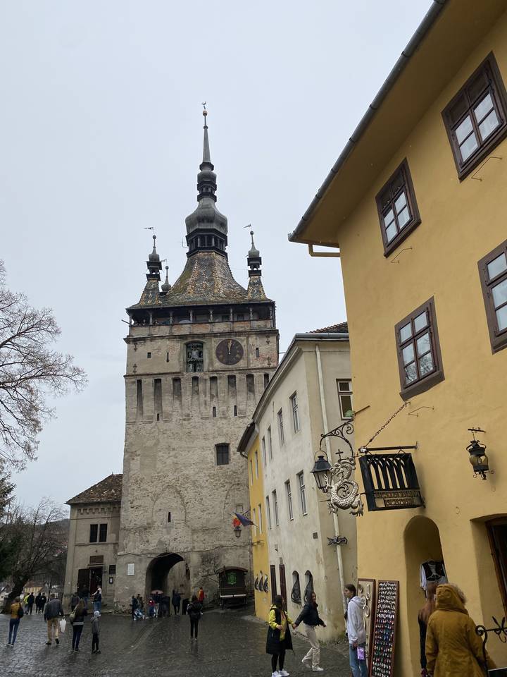 Historic clock tower in a town square with people walking.