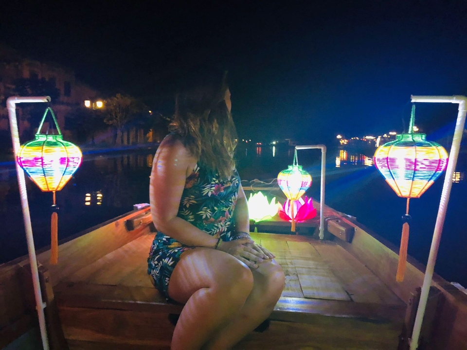 Woman in a boat with colorful lanterns at night.
