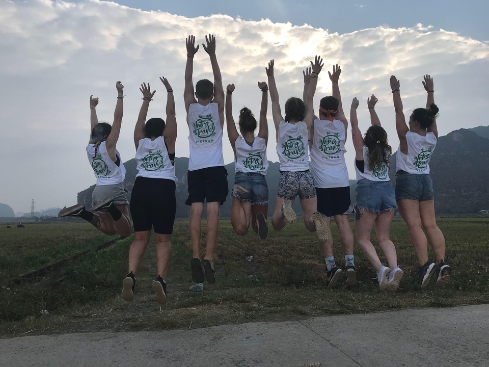 Group of young people jumping in a field.