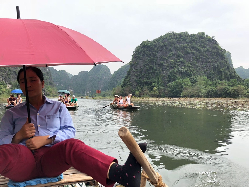People on boats enjoying a scenic river view with umbrellas.