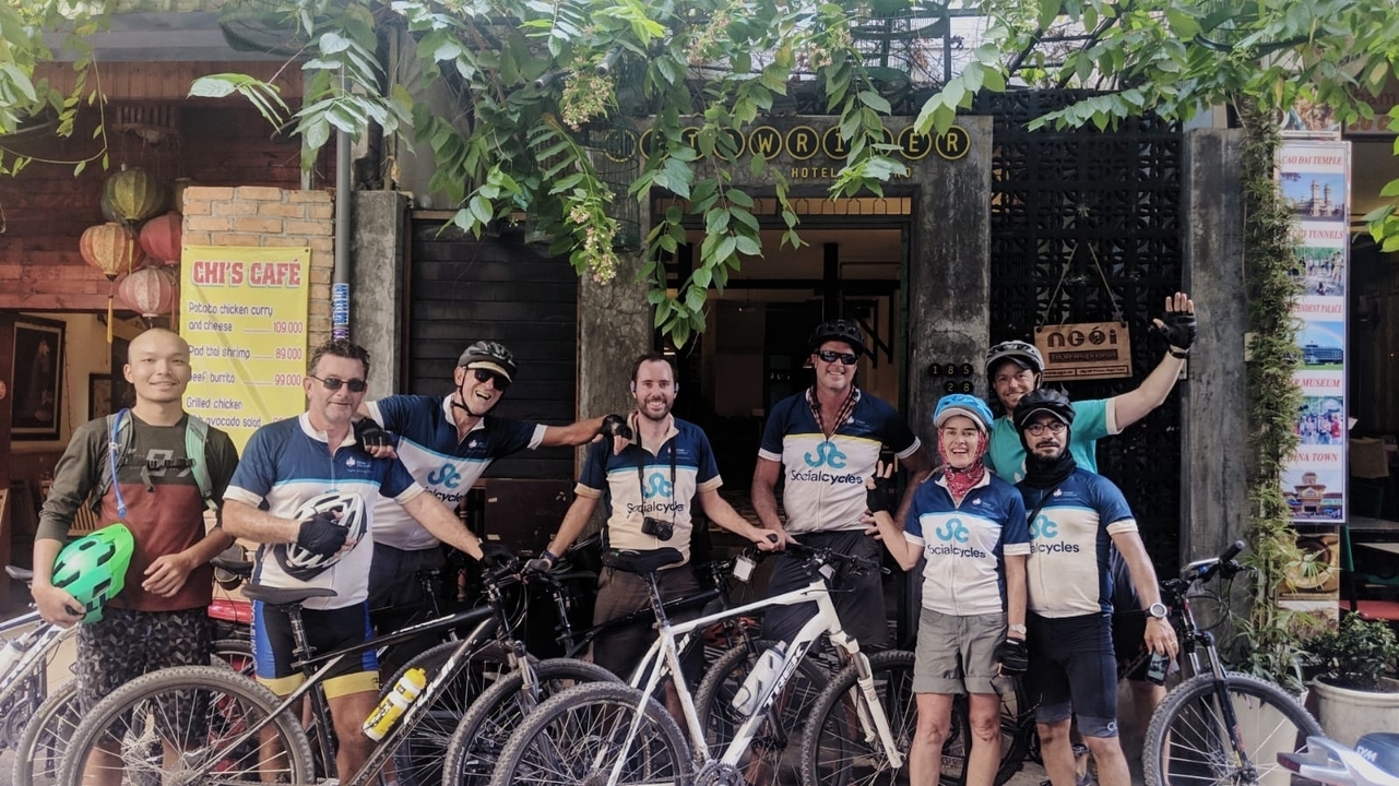 Groupe de cyclistes posant devant un café, portant des équipements de cyclisme.