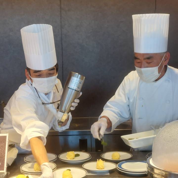 Chefs preparing dishes in a kitchen setting.