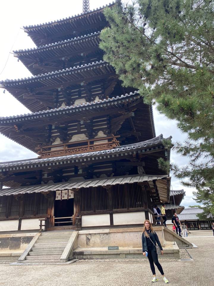 Person standing next to a multi-tiered pagoda.