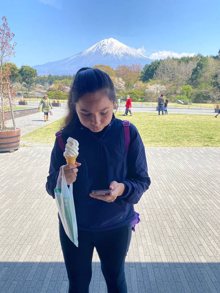 Person holding an ice cream cone with Mount Fuji in the background.