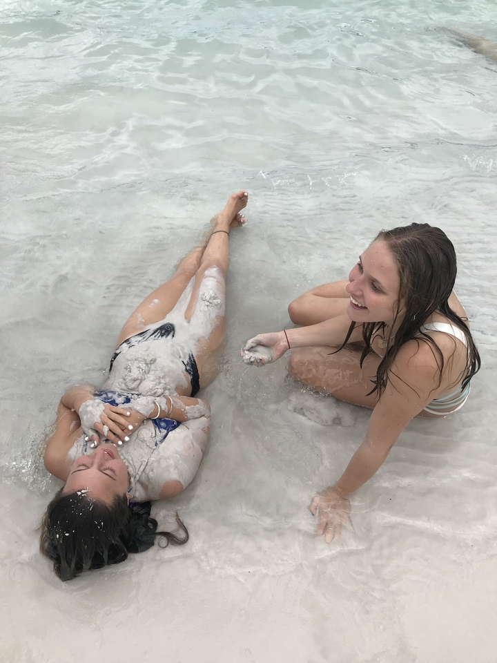 Two women covered in sand at a beach