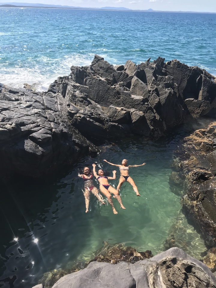 Three women floating in a natural rock pool.