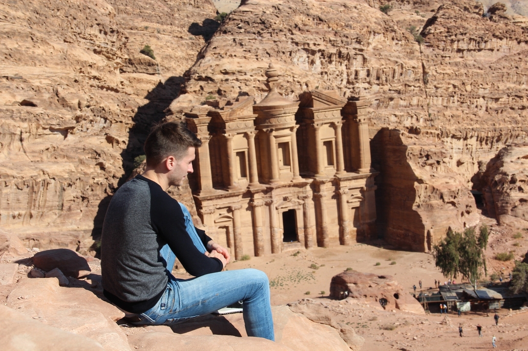 Person sitting on a ledge overlooking Al Deir (The Monastery) in Petra.