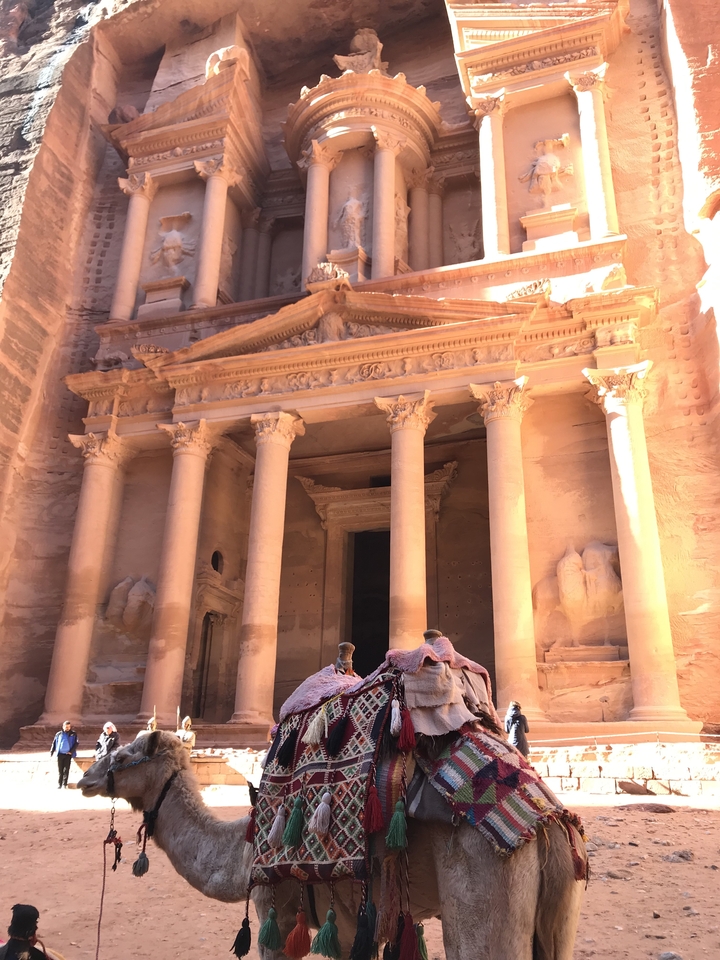 Front view of The Treasury at Petra with camel riders in foreground.