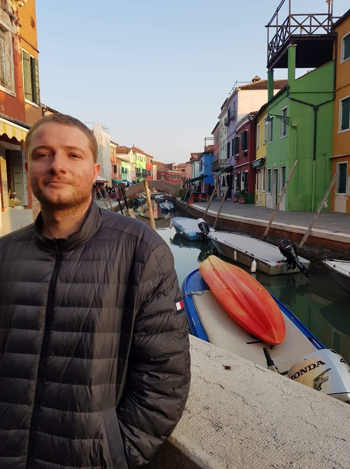 Person posing with a canal and colorful houses.