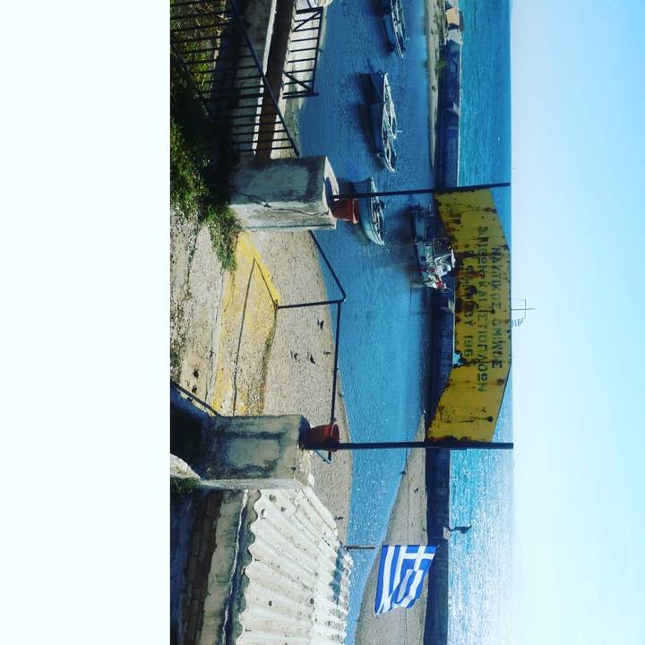 Seaside with boats and a Greek flag.
