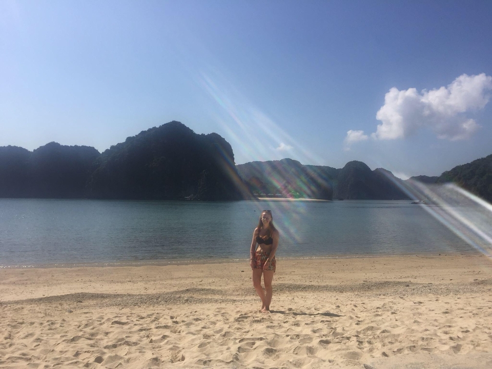 A person standing on a beach with mountains in the background.