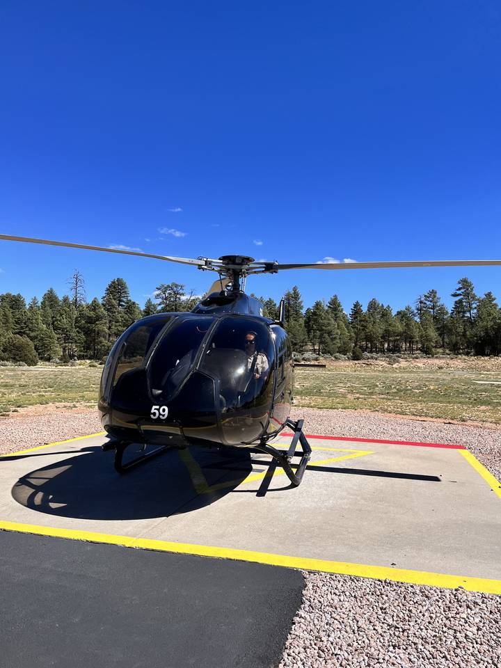 Helicopter parked on a helipad with clear sky background.