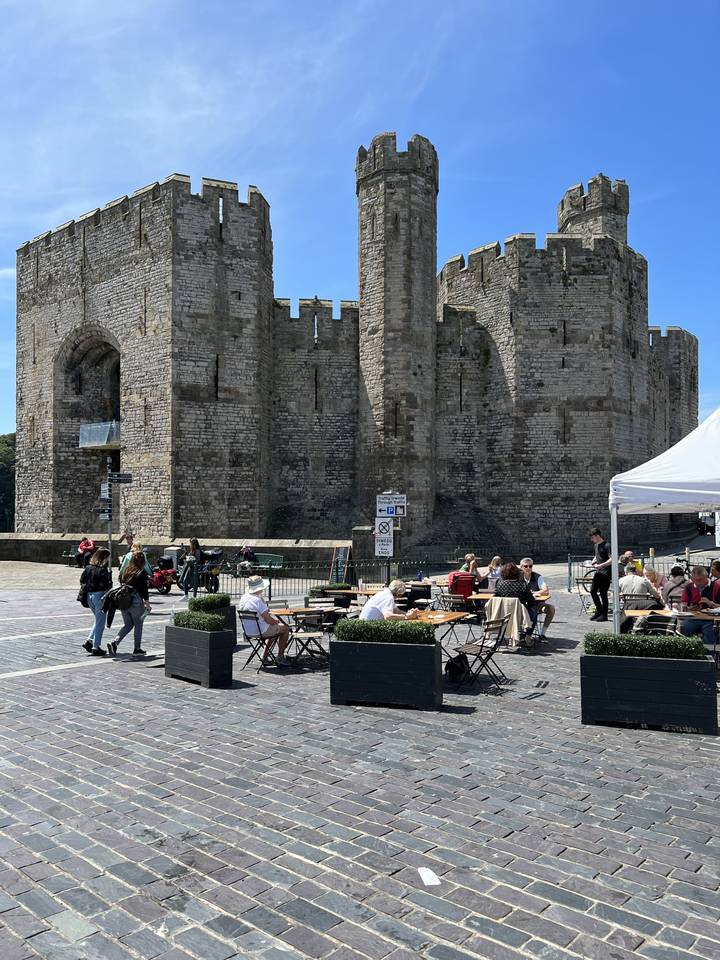 A medieval castle with people dining outside.