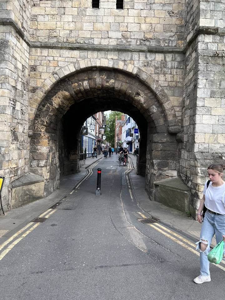 A stone archway leading to a busy street.