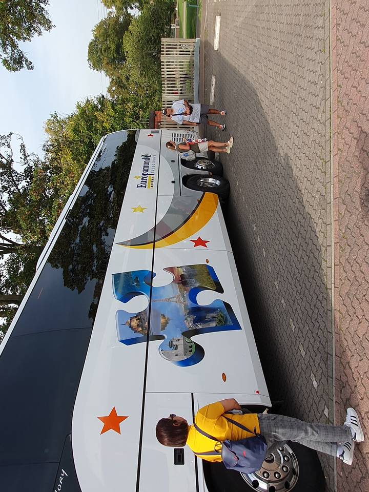 Large coach bus with passengers loading their luggage.