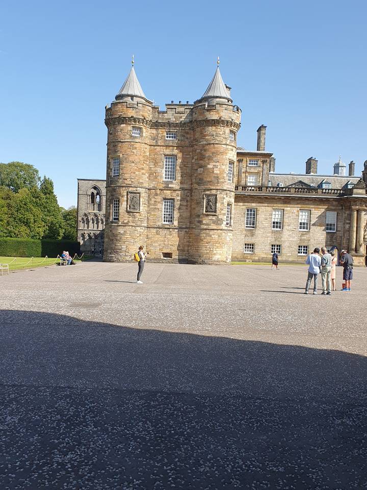 Castle with towers and an open courtyard, with people walking.