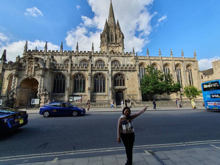 People walking along a historic gothic building with spires.