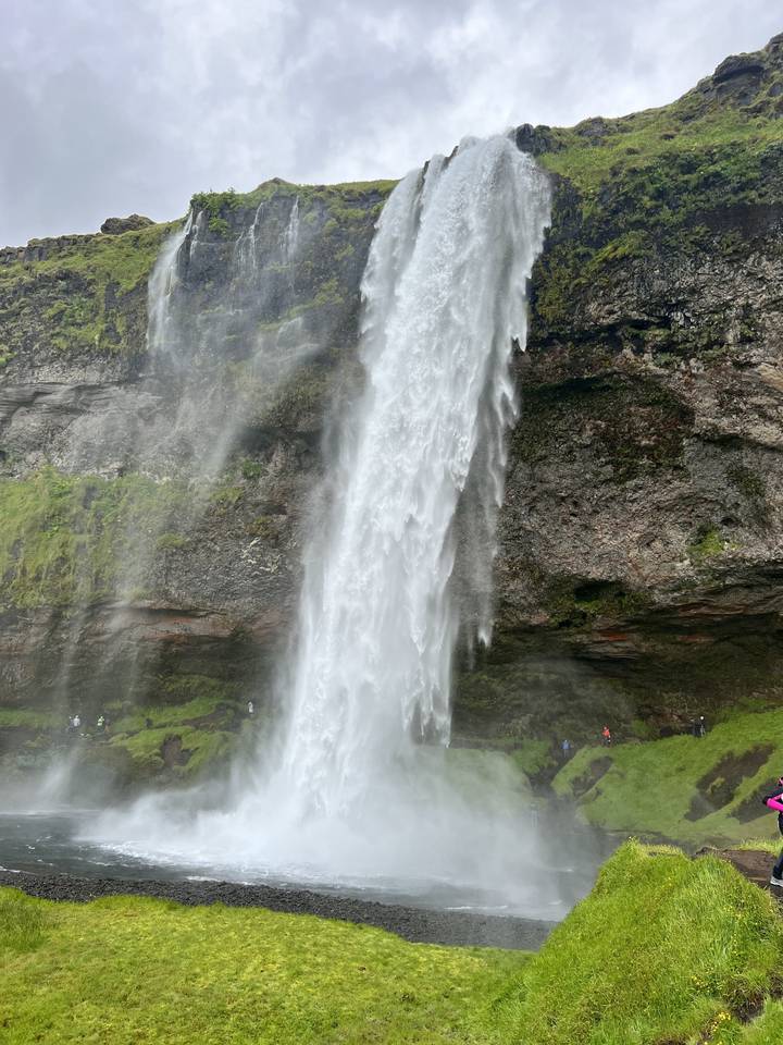 A tall waterfall cascading down a green cliff.