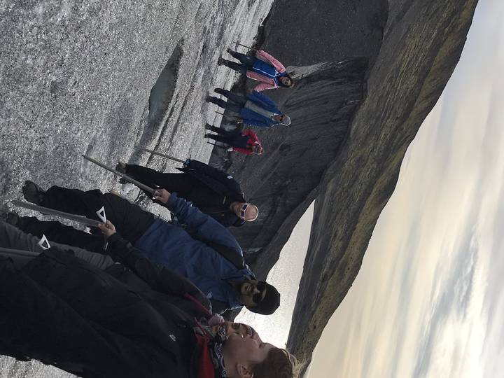 Group of people hiking on a glacier with gear.