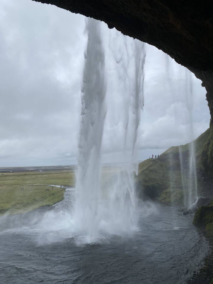 Waterfall seen from behind with a view of the landscape beyond.
