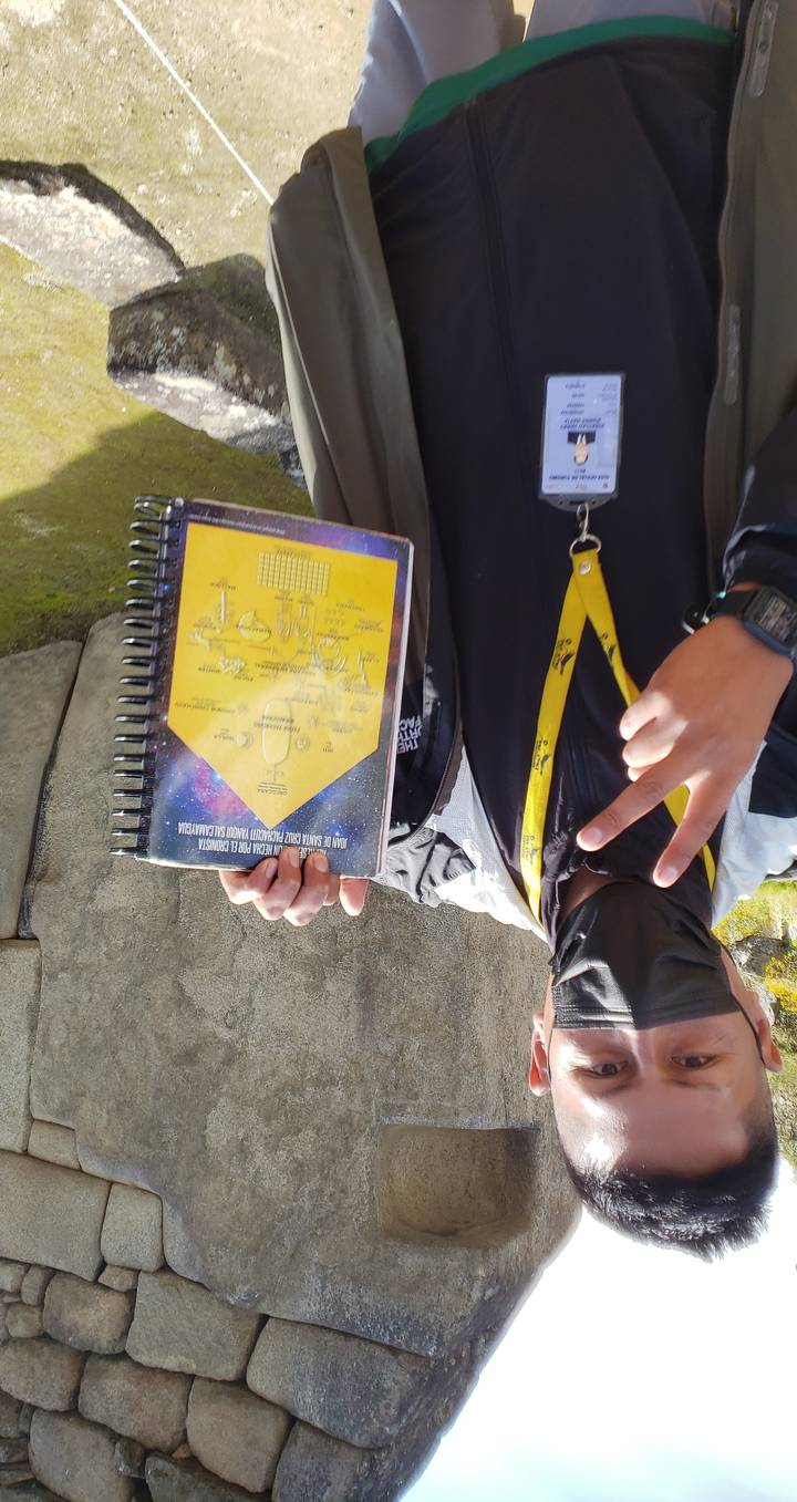 Man holding a notebook with Machu Picchu ruins.