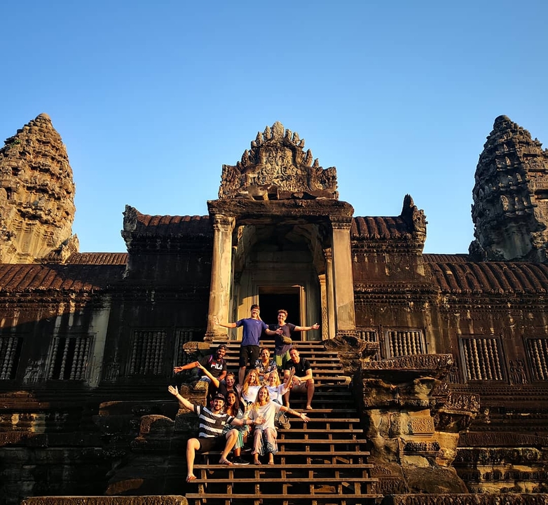 Group posing in front of an ancient temple with distinct architecture.