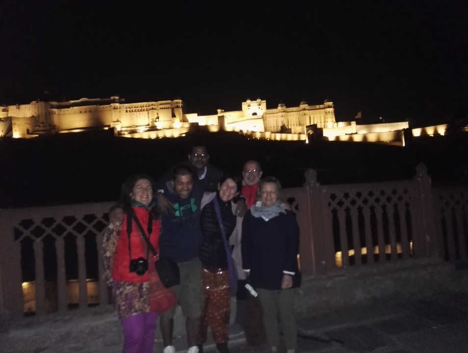 Group of people at night with an illuminated historic fort in the background.
