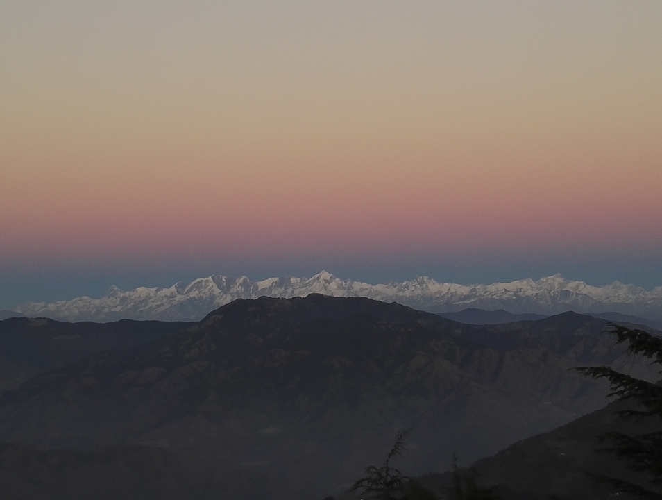 Mountain landscape with snow-capped peaks during sunset.
