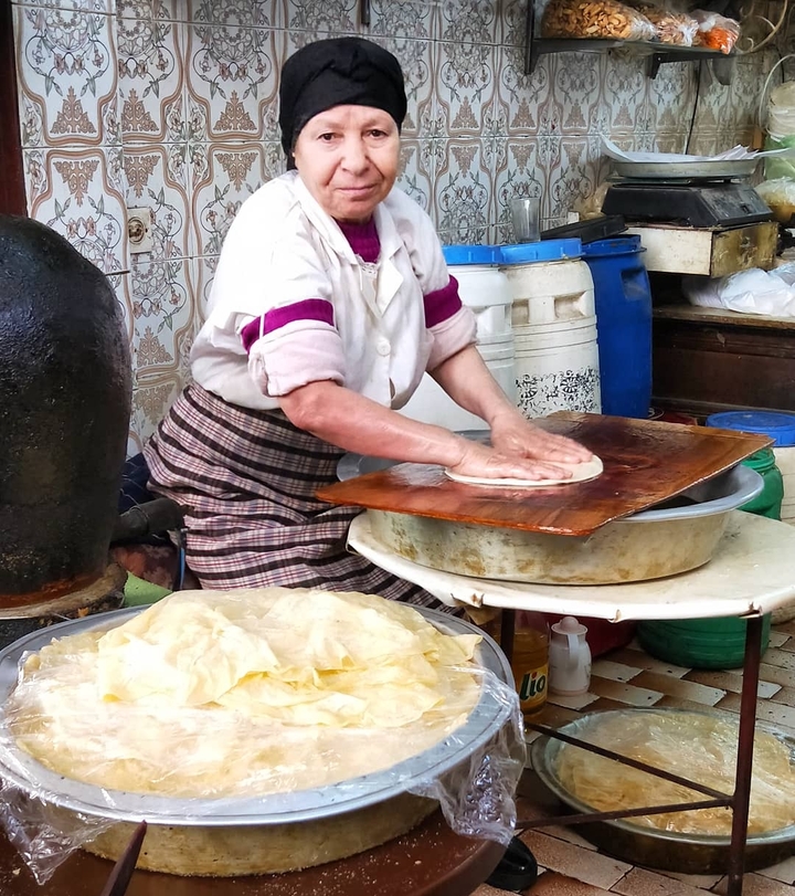 Person preparing flatbread in a traditional kitchen setting.