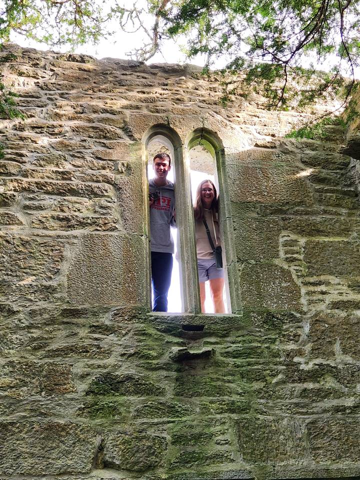 Two people posing inside a stone window frame.