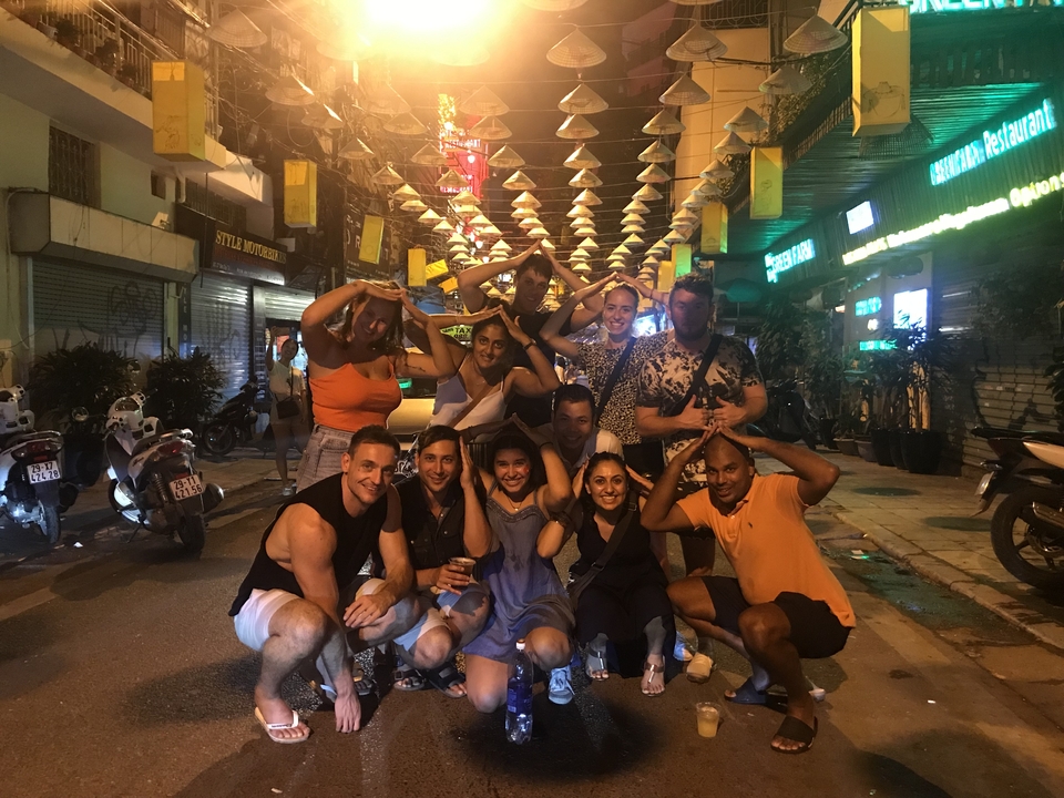 A group of people posing beneath hanging lights in a street.