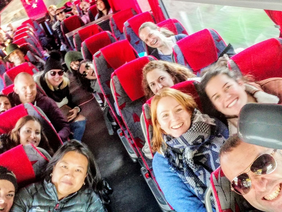 A group of people on a bus with bright red seats.