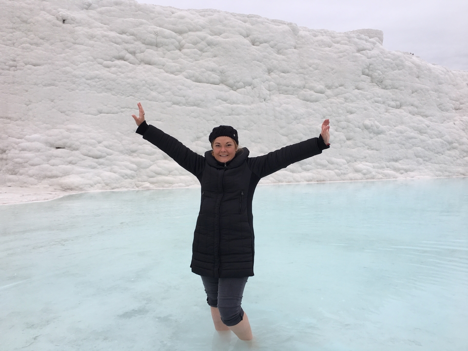 A person posing happily in front of a snowy pool.