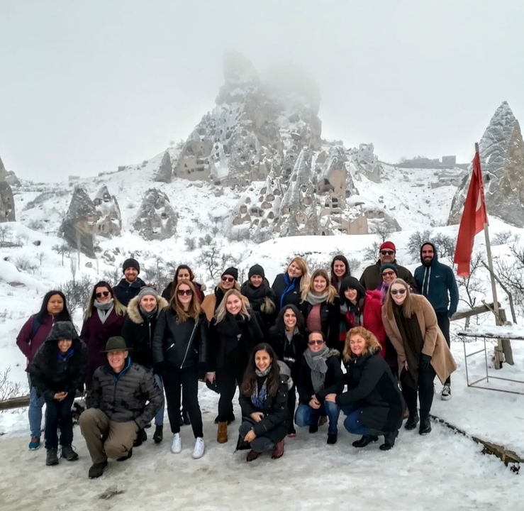 A group of people posed with a snowy landscape and caves nearby.