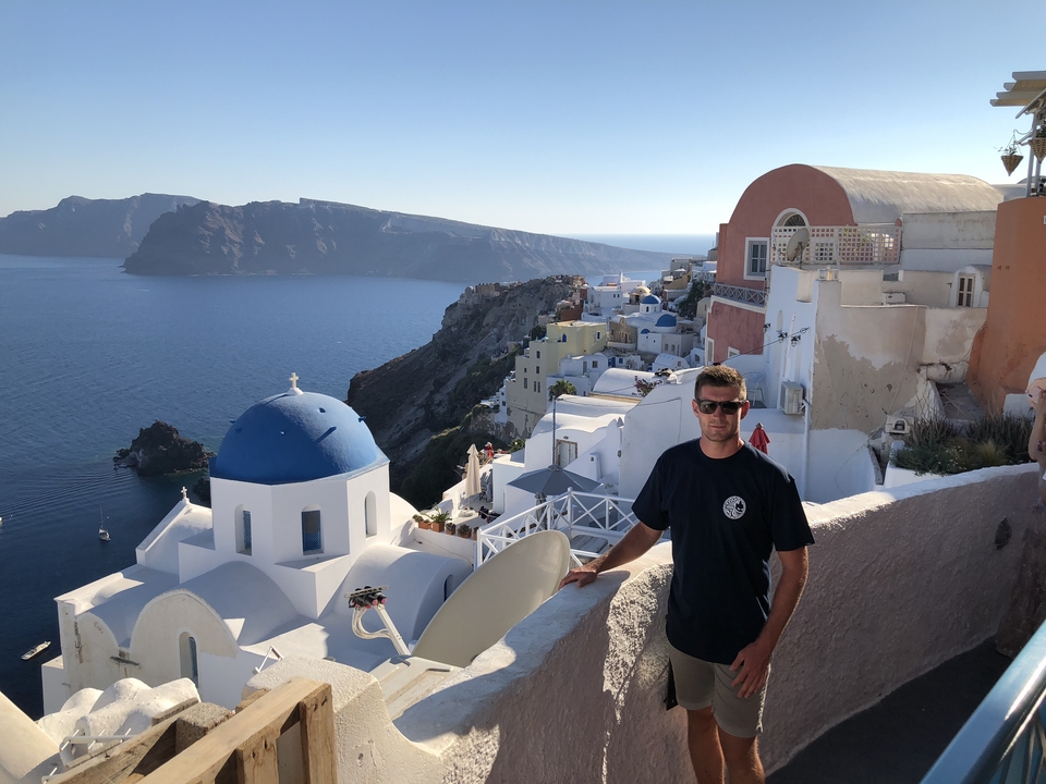 Person with a scenic backdrop of white buildings and ocean.