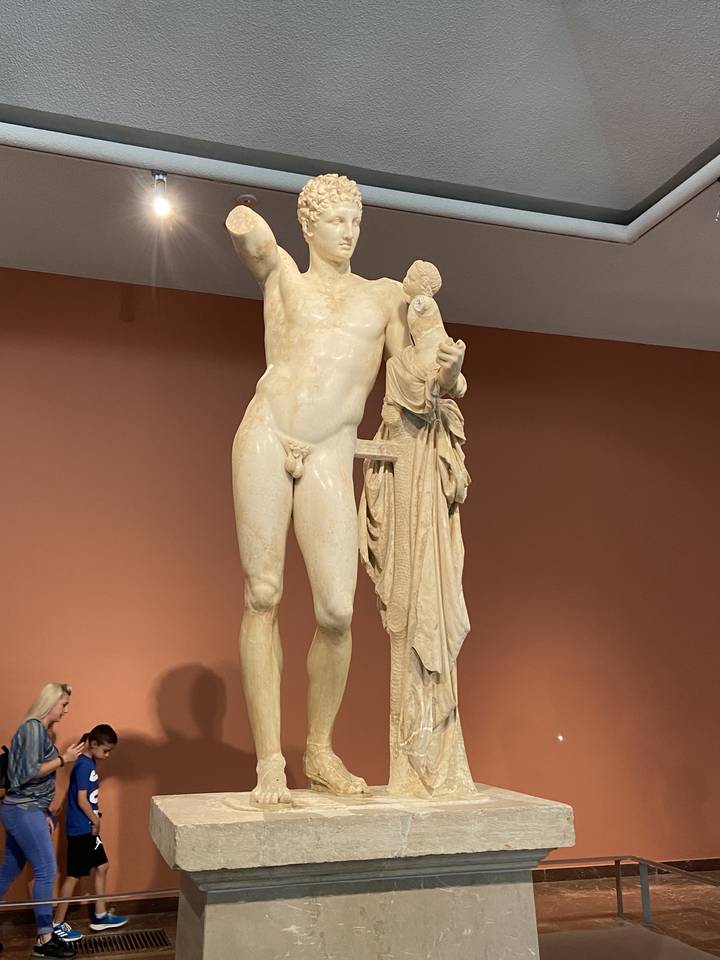 Statue grecque antique exposée dans un cadre muséal.