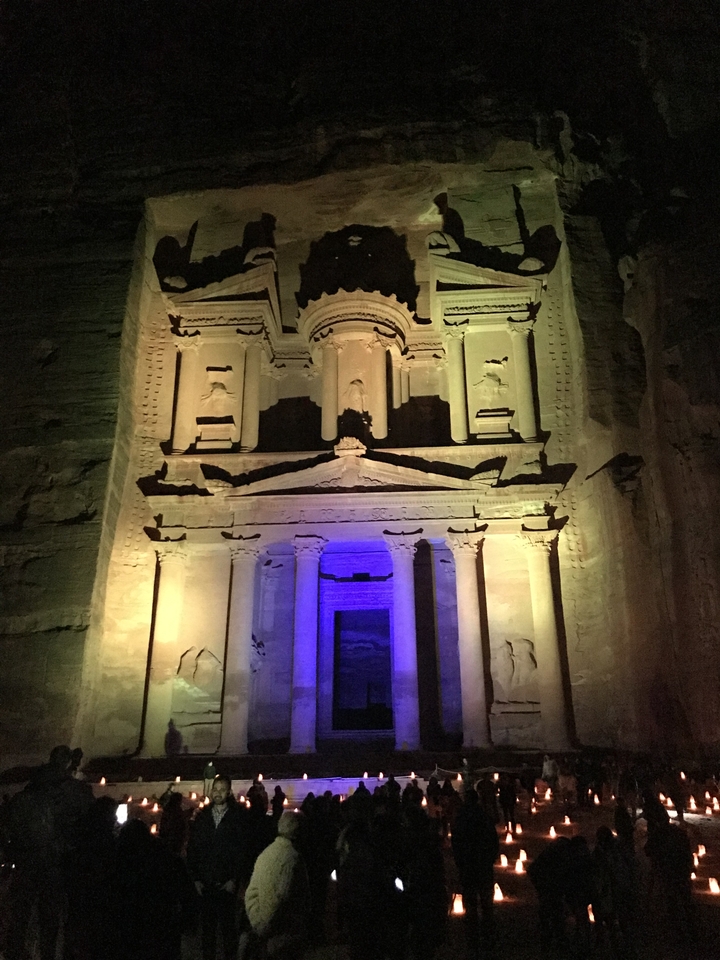 Petra's Treasury illuminated with colorful lights at night.