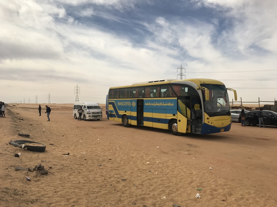 Tour bus and van parked in a desert area.