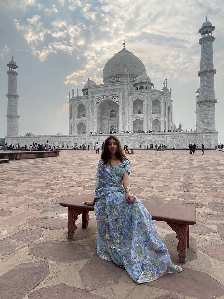 Person in traditional attire in front of the Taj Mahal.