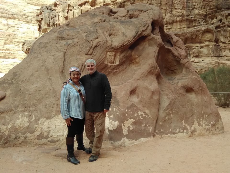 Two people in front of rock formations with carvings.