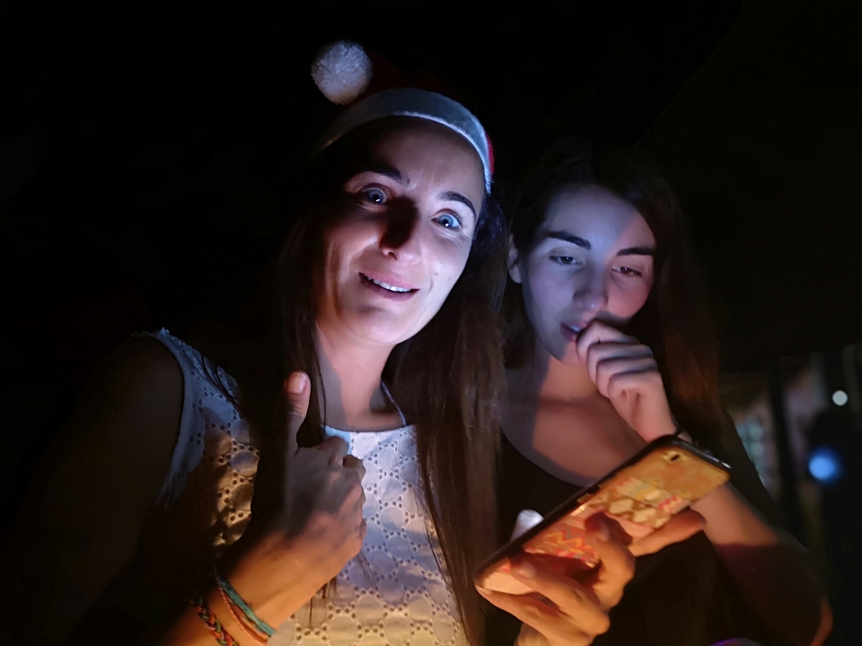 Deux femmes regardant un smartphone dans une lumière tamisée.