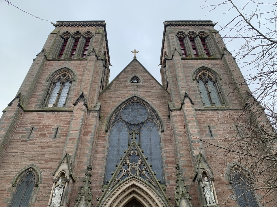 Facade of a grand brick cathedral with arches and stained glass.
