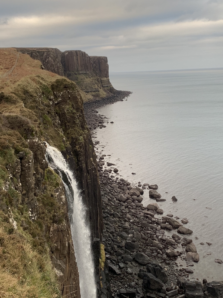 Waterfall cascading over a cliff into the ocean.