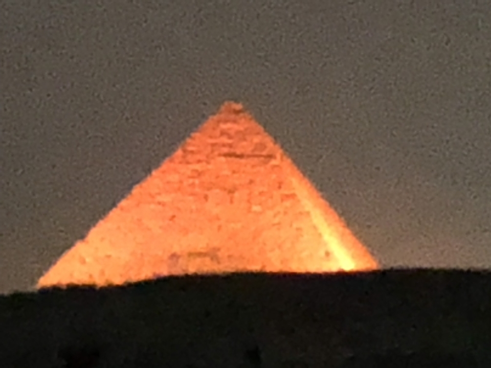 A blurry image of a pyramid at night.