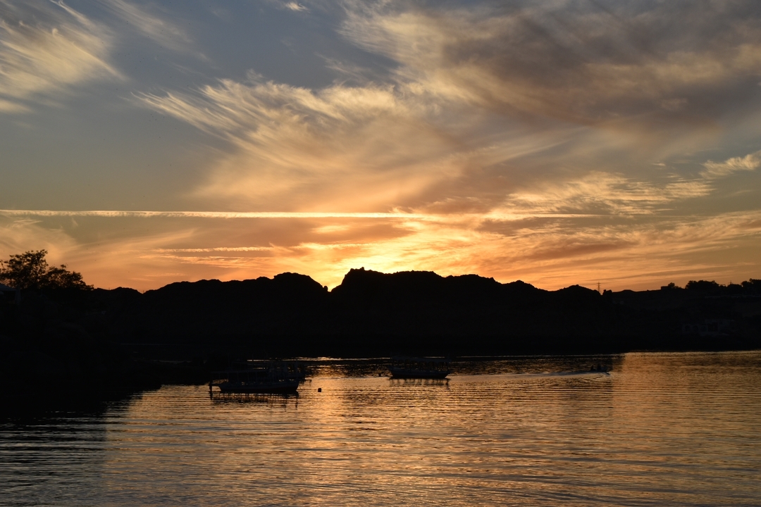 Beautiful sunset over a body of water with silhouettes of hills.