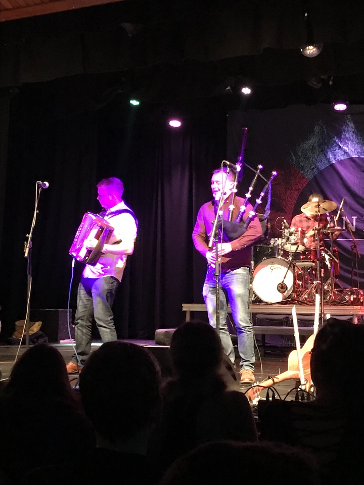 Musicians performing on stage with traditional Scottish instruments.