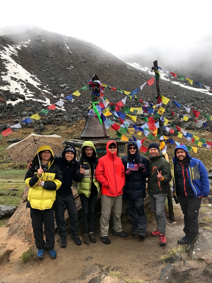 Groupe avec drapeau national posant près de drapeaux de prière.