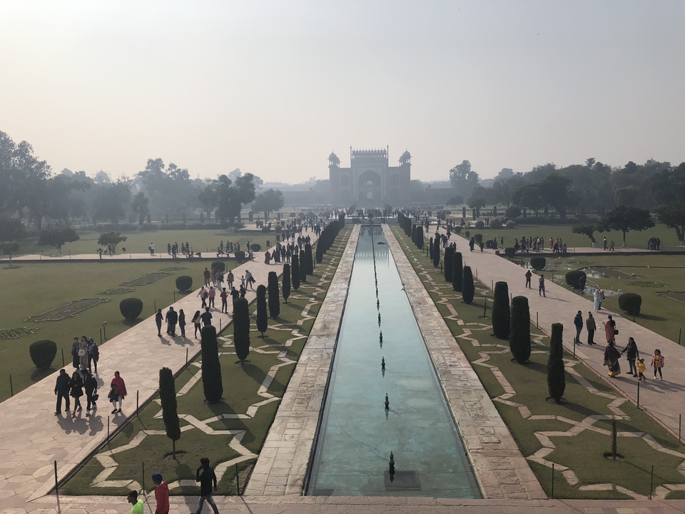 Tourists exploring the gardens and fountains of an Indian landmark.