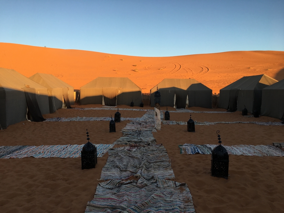 Desert camp with tents and decorative lanterns at sunrise.