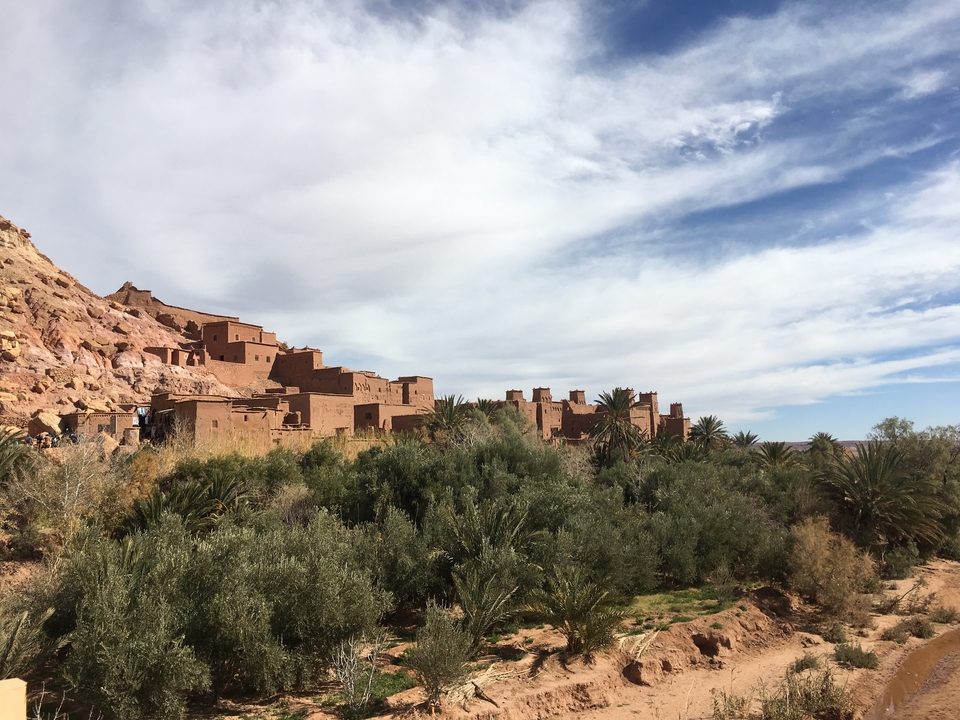 Desert town on a hillside under a cloudy sky.